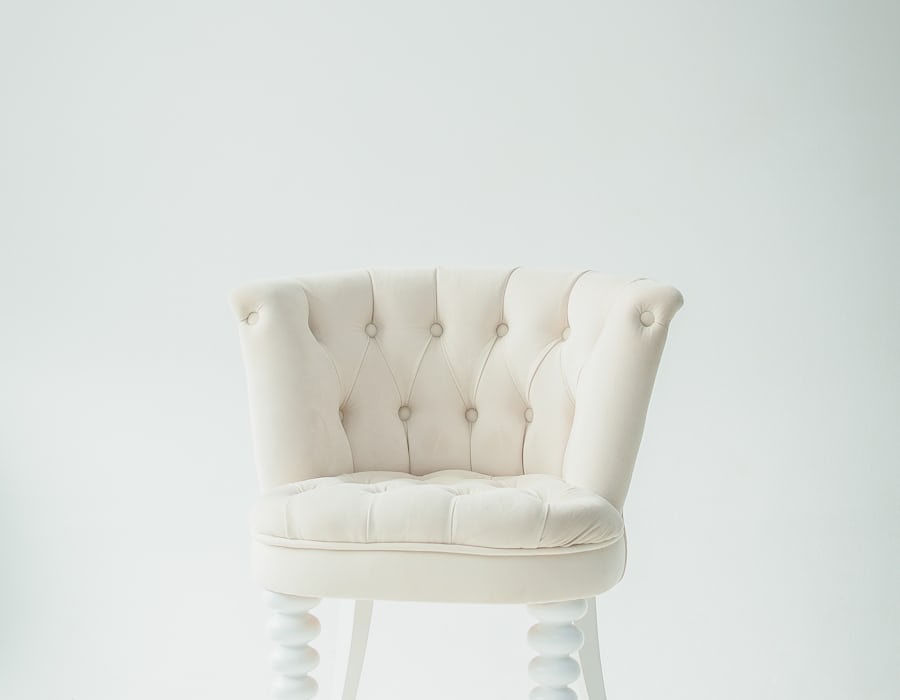 A carved oak dining chair with an aged leather seat